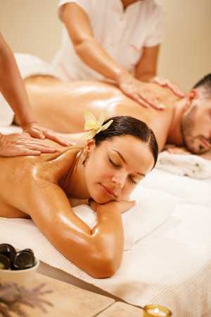 massage-duo (1) Young couple relaxing during back massage at health spa. Focus is on young woman.